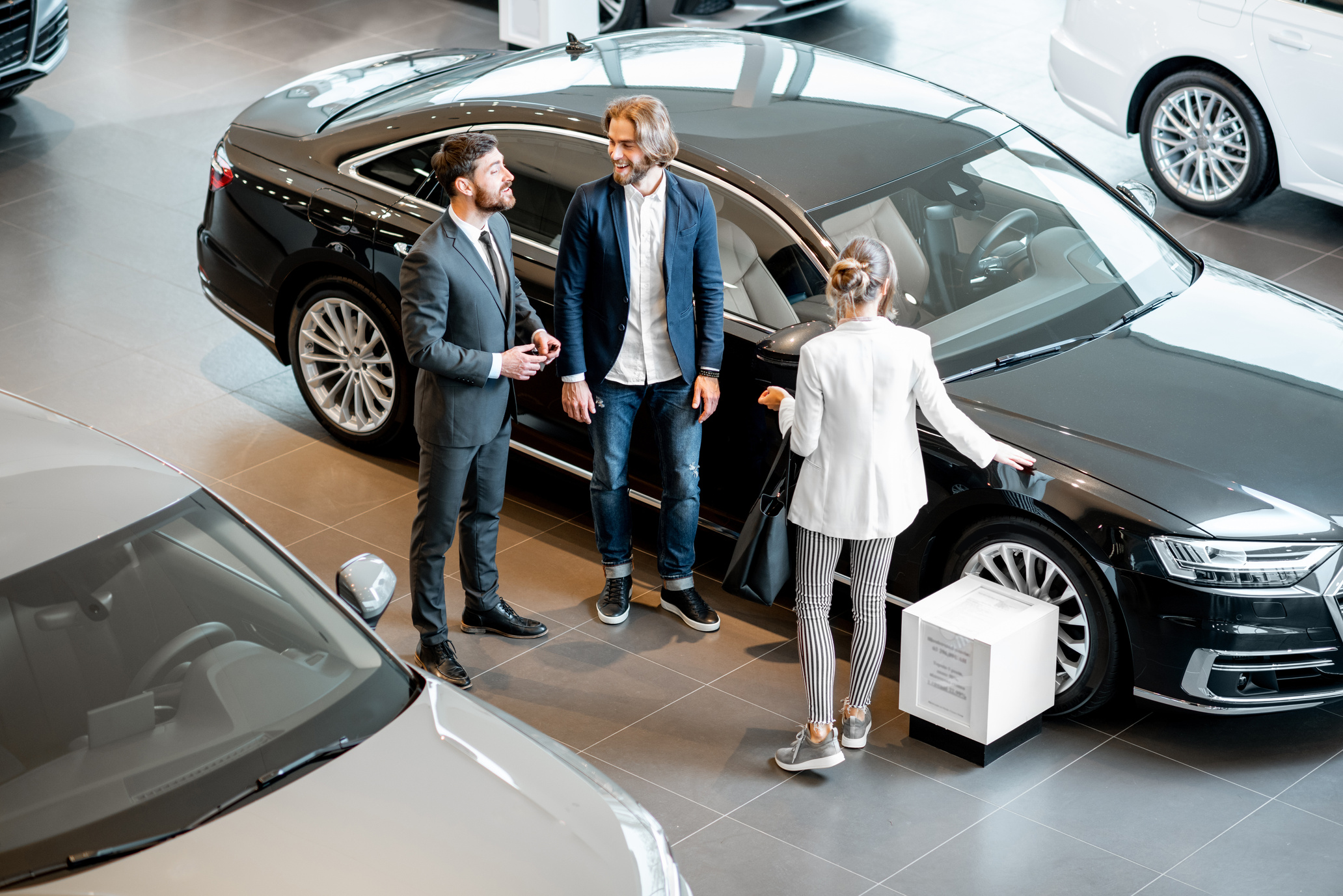 Business Couple with Salesperson in the Car Showroom